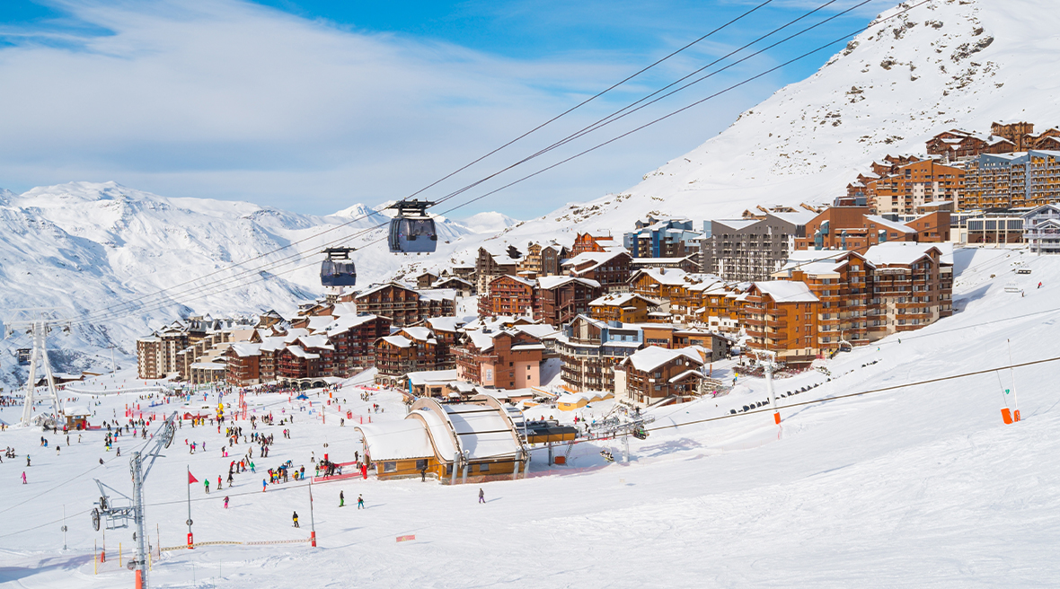 ski resort set into snowy mountainside with lots of people skiing the slopes